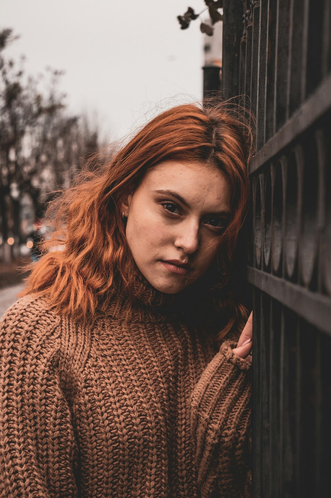 Portrait of a woman with auburn hair in an orange sweater